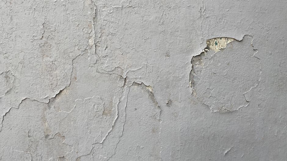 Weathered wall with peeling paint and cracks.