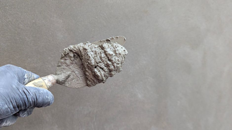 Hand holding a trowel loaded with plaster.